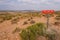 Stay on Trail poster  in the middle of desert on unpaved road