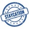 STAYCATION text on blue grungy round rubber stamp
