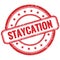 STAYCATION text on red grungy round rubber stamp