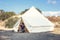 Staycations - local camping outdoor vacation. Woman drinking tea near big glamping tent with cozy interior. Luxury travel