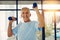 Staying active means aging well. Portrait of a fit senior smiling while lifting weights at the fitness center.