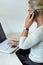 Staying constantly connected. A senior woman using her laptop while making a phone call at home.