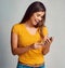 Staying social with the vast world online. Studio shot of an attractive young woman using a cellphone against a grey