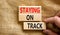 Staying on track symbol. Concept words Staying on track on wooden blocks on a beautiful canvas background. Businessman hand.