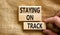 Staying on track symbol. Concept words Staying on track on wooden blocks on a beautiful canvas background. Businessman hand.