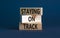 Staying on track symbol. Concept words Staying on track on wooden blocks on a beautiful grey table grey background. Business,