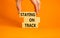 Staying on track symbol. Concept words Staying on track on wooden blocks on a beautiful orange background. Businessman hand.
