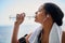 Staying well hydrated throughout her workout. a sporty young woman drinking water while out for a run.