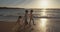 Steadicam shot of three young kids running on the beach during sunset