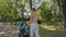 Steadicam shot of young mother pushing baby`s pram in park