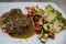 Steak cooked rare, smothered in a tasty gravy and paired with grilled vegetables: broccoli, bell peppers and zucchini