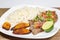 A steak covered in pico de gallo surrounded by plantains and white rice on a white plate. Cuban food.