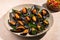 Steam cooked mussels with Vinaigrette garnish on beige plate, top view, Mediterranean cuisine.