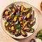 Steam cooked mussels with Vinaigrette garnish on beige plate, top view, Mediterranean cuisine.