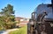 Steam locomotive drives past a sports field with a church tower in the background. Dynamic due to motion blur