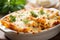 Steam rising from a delicious baked ziti, served in a white ceramic dish with melted cheese on top and sprinkled with fresh herbs