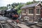 Steam train approaching Levisham historic railway station showing tracks and crossing