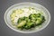 Steamed brocolli with cream sauce and parmesan. Isolated on a white background