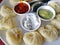 Steamed Nepali traditional momos dumplings are served with different sauces.