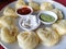 steamed Nepali traditional momos dumplings are served with different sauces.