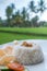 Steamed rice with prawn crackers and vegetables on white plate over blurred rice fields