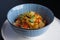 Steamed veggies in white cup with blue pattern on the black table