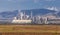 Steaming coal power plant over yellow agriculture field on the mountains background. Greece. Nature environment pollution concept.