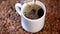 A steaming hot dark coffee is being poured into a white ceramic mug