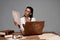 Steampunk woman in glasses with documents and vintage laptop at workplace isolated on grey