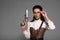 Steampunk woman holding vintage pistol and touching glasses isolated on grey