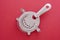 Steel bartender strainer, on a red background. view from above. close-up