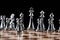 Steel chess figures standing on wooden chessboard