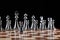 Steel chess figures standing on wooden chessboard