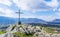 A steel cross on top hill of the mountain and rays of the sun on a blue skies background.