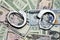Steel handcuffs above US dollar banknotes, tax evasion concept