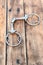 Steel horse snaffle-bit on wooden background.