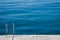 Steel ladder on pier with turquoise adriatic ocean in Triest