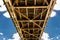 Steel lattice construction of a railway bridge on a background of blue sky with white clouds.