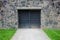 Steel metal gate or door in an old stone wall, garage, green lawn.