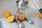 steel metal manual press juicer with cut oranges and glass on the kitchen table at home