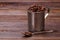 Steel mug and teaspoon filled with coffee beans.