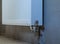 A steel radiator without a tap hangs on the wall. The concept of radiator installation, plumbing work and home renovation