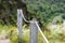 A steel rope passing through the meshes of metal posts over the cliff.