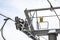 Steel ropes over wheels in mechanism on top of ski chair lift support pillar, number 6 on yellow plate, bright sky background