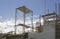 The steel scaffolding with brown rust standing on the top floor of the building under white fluffy clouds and blue sky