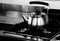 Steel teapot above the industrial cooker with black and white ef