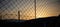 Steel wire mesh fence on a sunset background. Blurred city and hills silhouette.