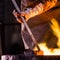 Steel worker in protective clothing raking furnace in an industrial foundry