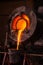 Steel worker raking furnace in an industrial foundry