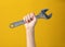 steel wrench in man hand on yellow background. Tool for repair or construction. Symbol is ready to work
